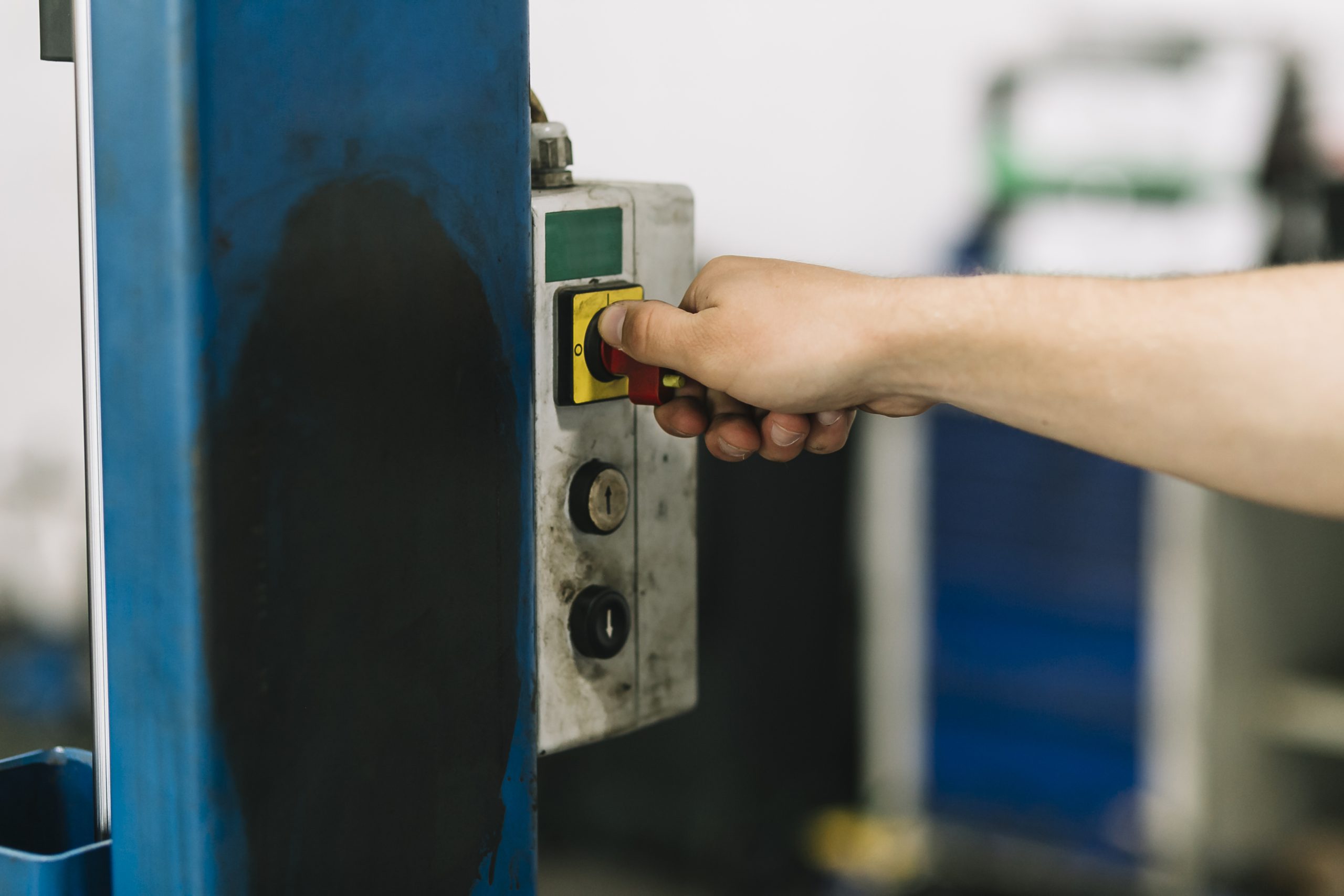 Zbliżenie na rękę operatora wykonującą obsługę maszyny poprzez przekręcenie czerwonego przełącznika na starym, zabrudzonym panelu sterowniczym -
automatyka budynkowa ostrów wielkopolski