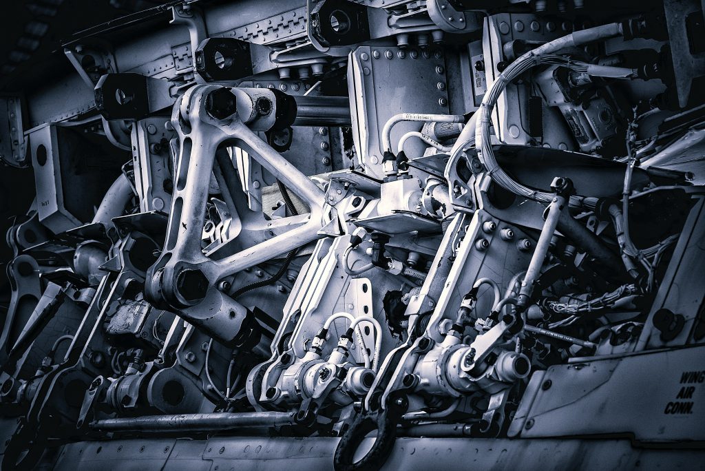 Na zdjęciu widać złożony układ mechaniczny zbudowany z metalowych elementów, przegubów, śrub i przewodów