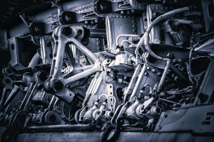 Na zdjęciu widać złożony układ mechaniczny zbudowany z metalowych elementów, przegubów, śrub i przewodów