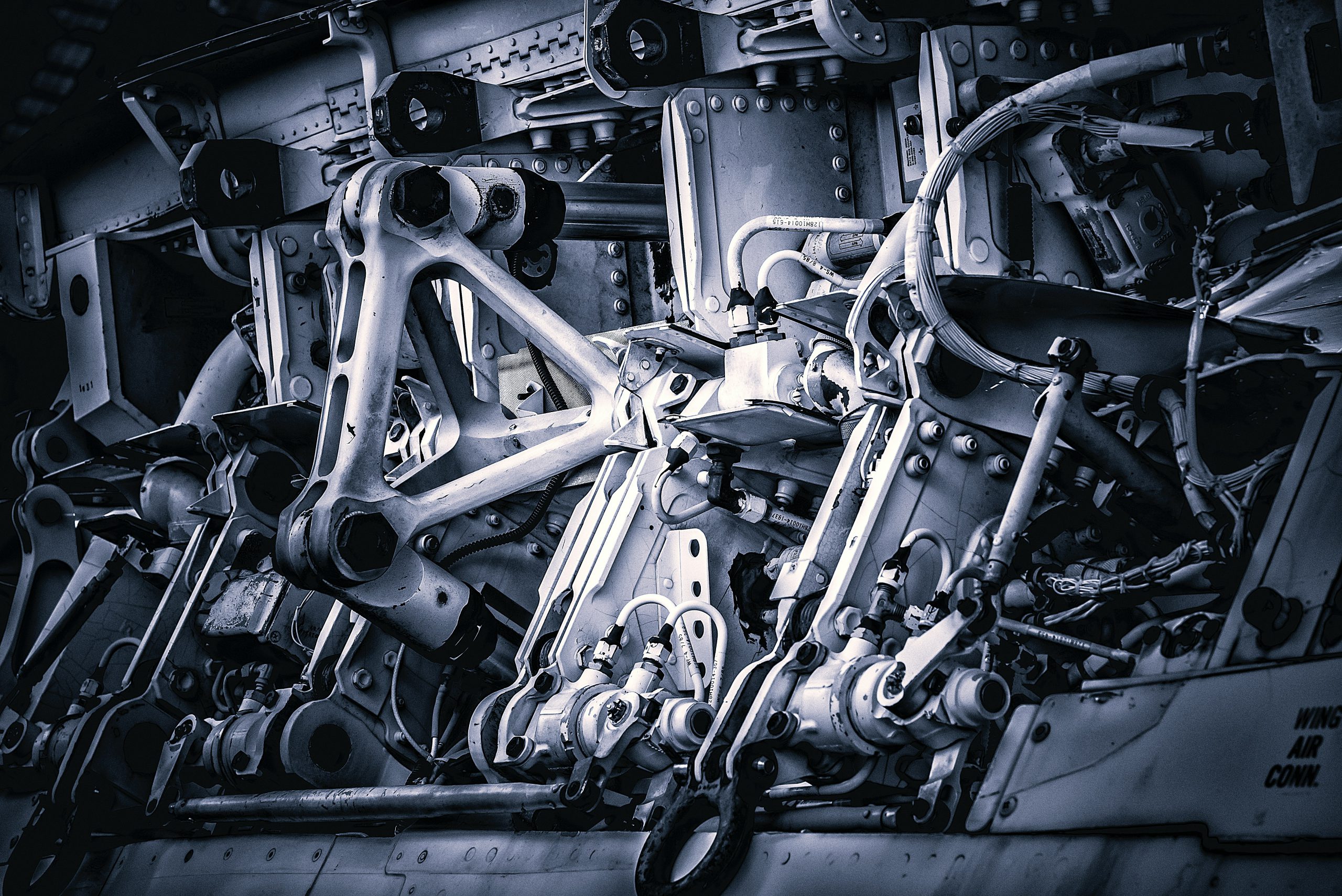 Na zdjęciu widać złożony układ mechaniczny zbudowany z metalowych elementów, przegubów, śrub i przewodów